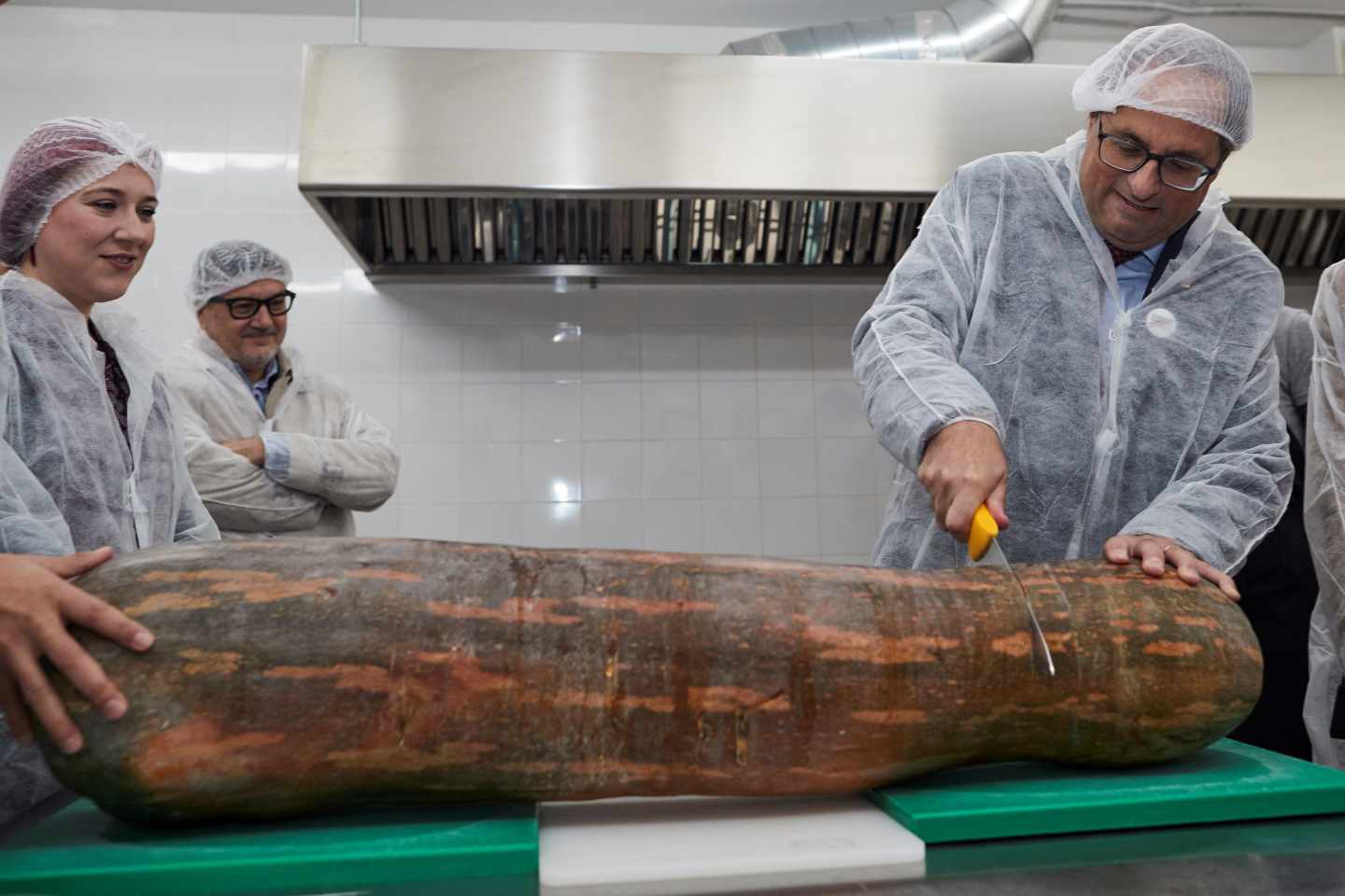 Quim Torra corta una enorme calabaza durante su visita a una empresa catalana.