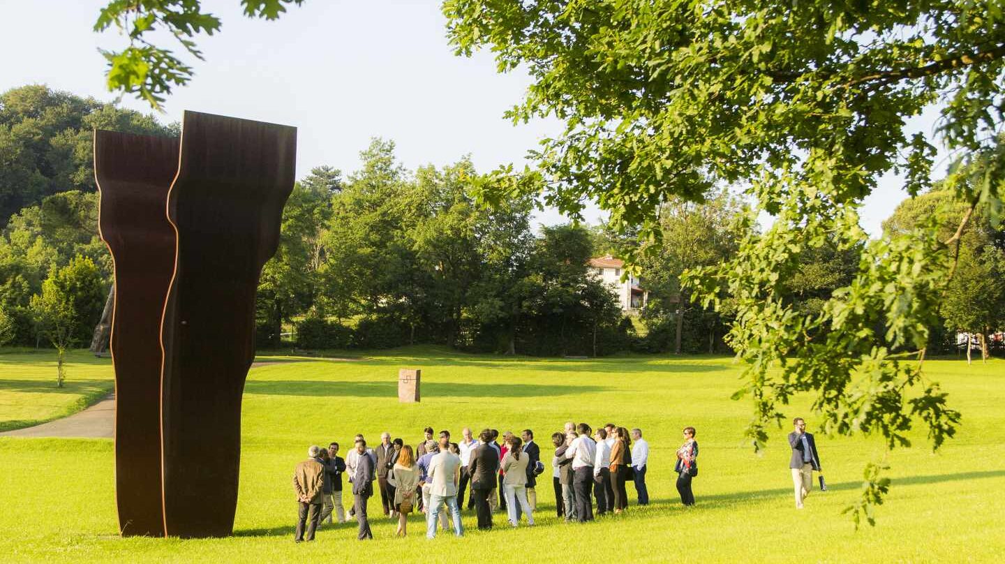 Grupo visitando Chillida Leku bajo la sombra de Buscando la luz I (acero corten, 1997).