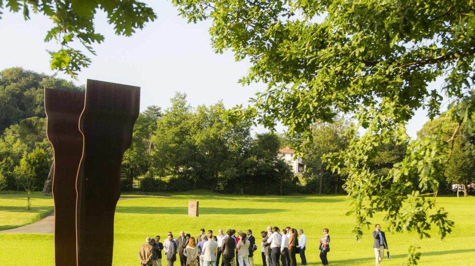 Grupo visitando Chillida Leku bajo la sombra de Buscando la luz I (acero corten, 1997).