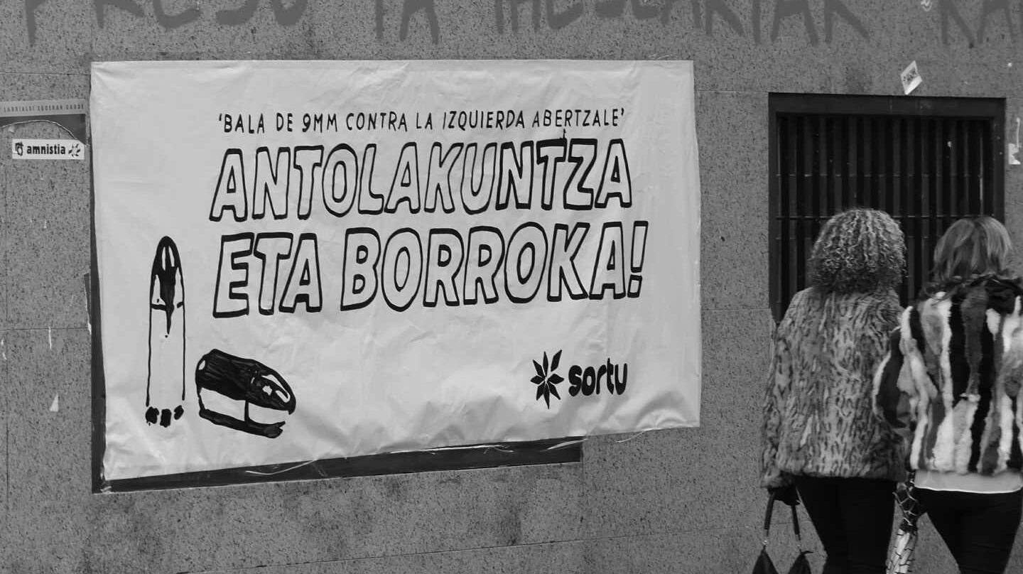 Dos mujeres pasan frente a una pancarta con el lema "Bala de 9mm contra la izquierda abertzale".