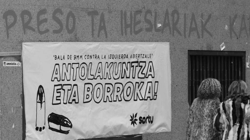 Dos mujeres pasan frente a una pancarta con el lema "Bala de 9mm contra la izquierda abertzale".