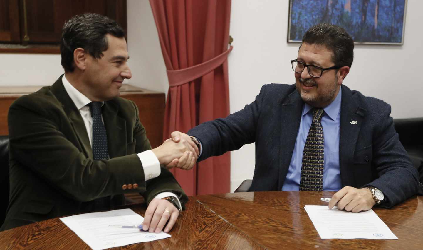 Juan Manuel Moreno estrecha la mano con el líder andaluz de Vox, Francisco Serrano.