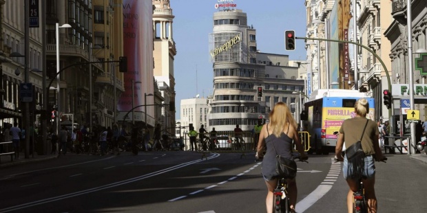 Dos personas circulan en bicicleta por la Gran Vía de Madrid