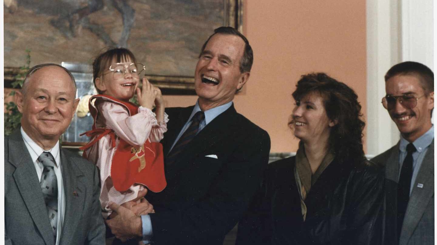 El ex presidente de Estados Unidos, George H.W. Bush sostiene en brazos a Jessica McClute, la niña rescatada de un pozo tras 58 horas atrapada