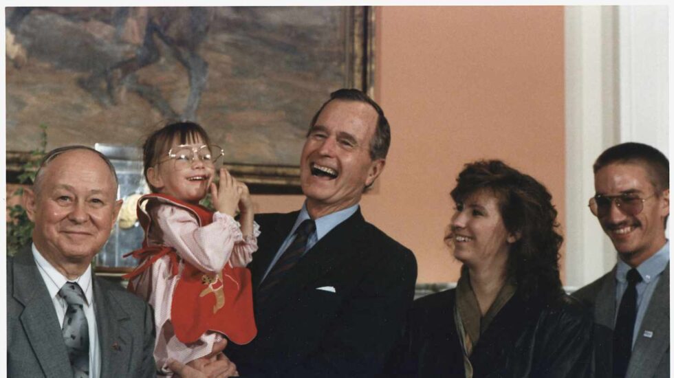 El ex presidente de Estados Unidos, George H.W. Bush sostiene en brazos a Jessica McClute, la niña rescatada de un pozo tras 58 horas atrapada
