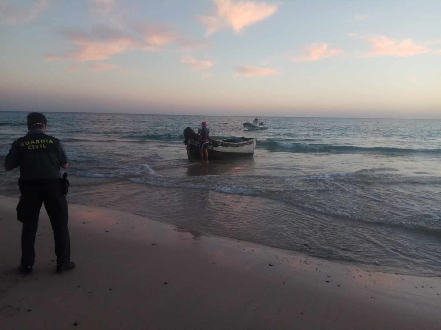 Un agente de la Guardia Civil frente a una patera en el Estrecho.