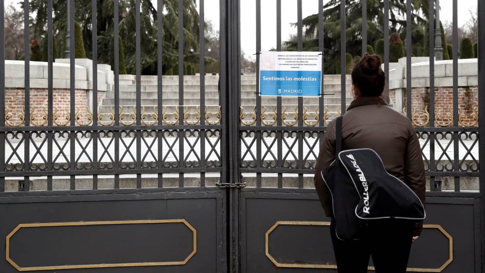 Una mujer observa un cartel que anuncia el cierre del parque del Retiro.