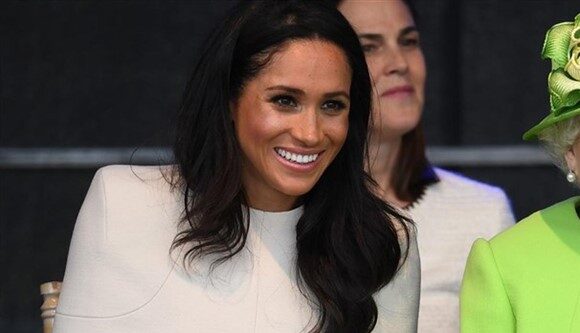 Meghan Markle sonriendo, con la reina Isabel II de Inglaterra vestida de verde sentada a su lado