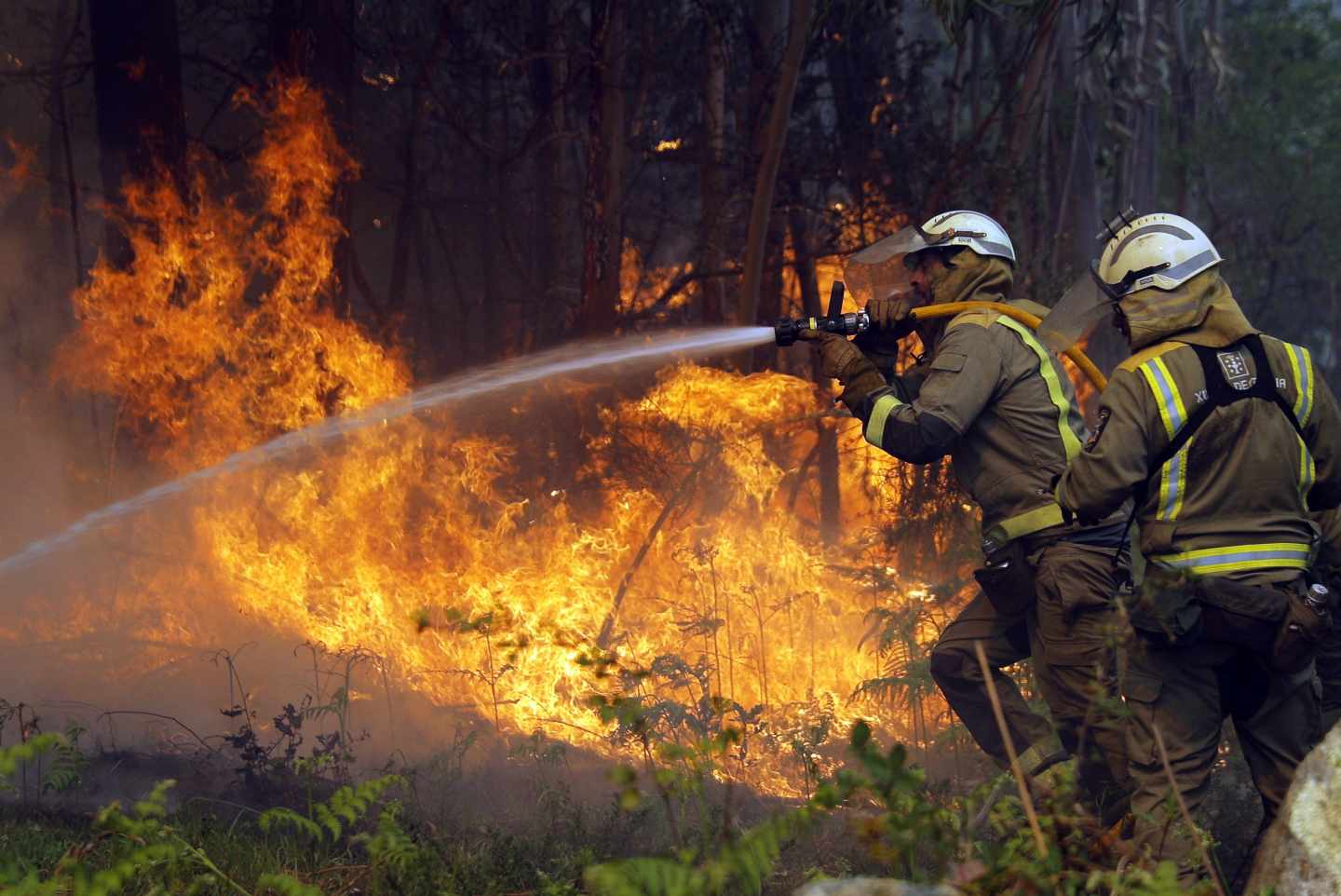 Los bomberos apagan uno de los numerosos focos del incendio en la localidad coruñesa de Rianxo