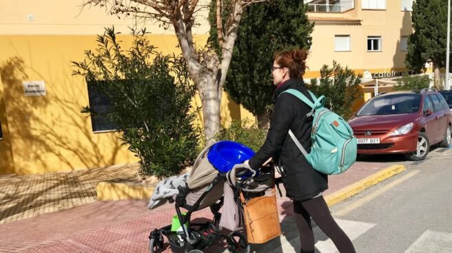 Una mujer cruza un paso de peatones con un carrito de bebé.