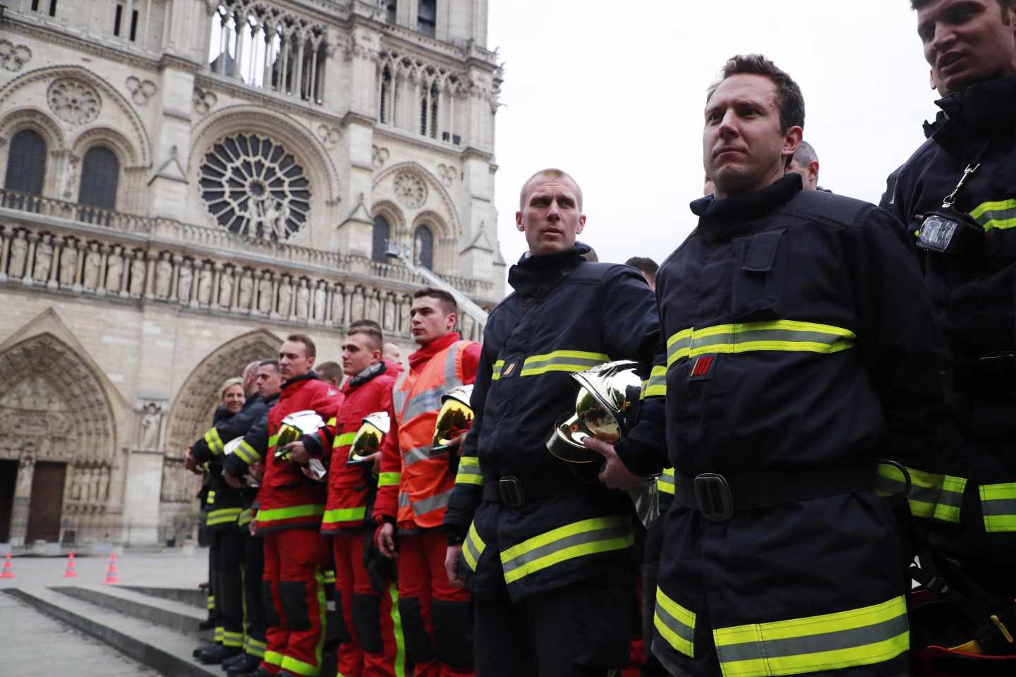 Un grupo de bomberos esperan la llegada del ministro del Interior ante Notre-Dame.