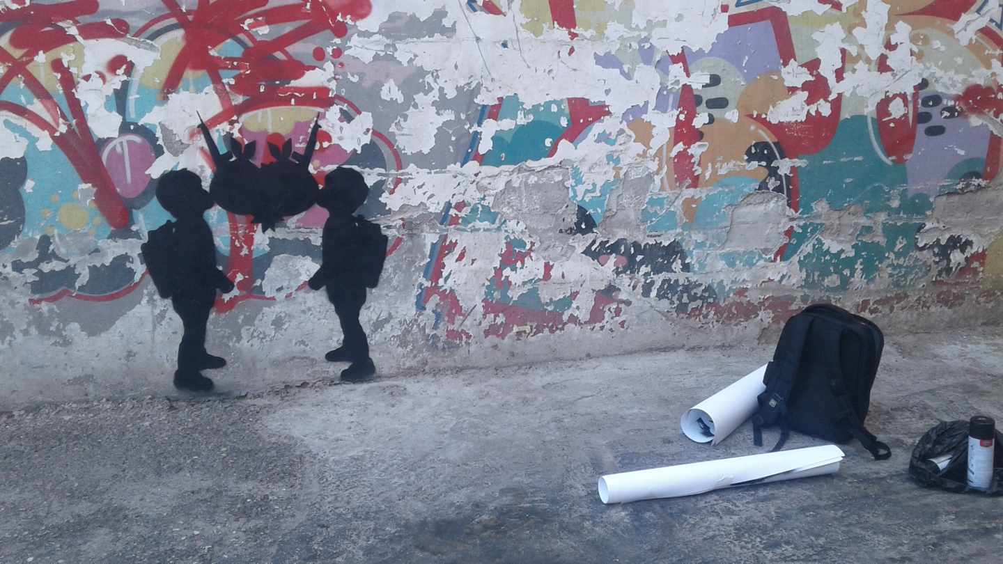 Dos niños, que representan cada uno de ellos a las partes del conflicto palestino-israelí, se besan simbolizando el amor, la violencia política o, "simplemente", la indiferencia. Dos pompas de chicle, unas granadas y dos armas conforman el corazón que surge de este beso.