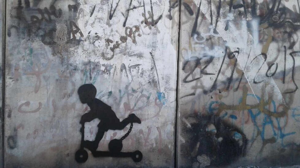 A través de este niño montado en un patinete y con un grillete con bola enganchado a su tobillo, Cake $ representa "la ocupación y lucha diaria" con la que lidian los palestinos.