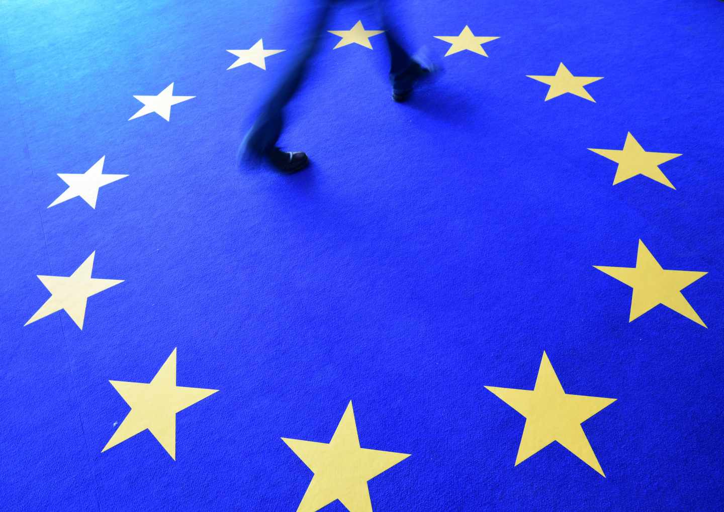Un hombre pasa por un alfombra con las estrellas de la bandera de la UE.