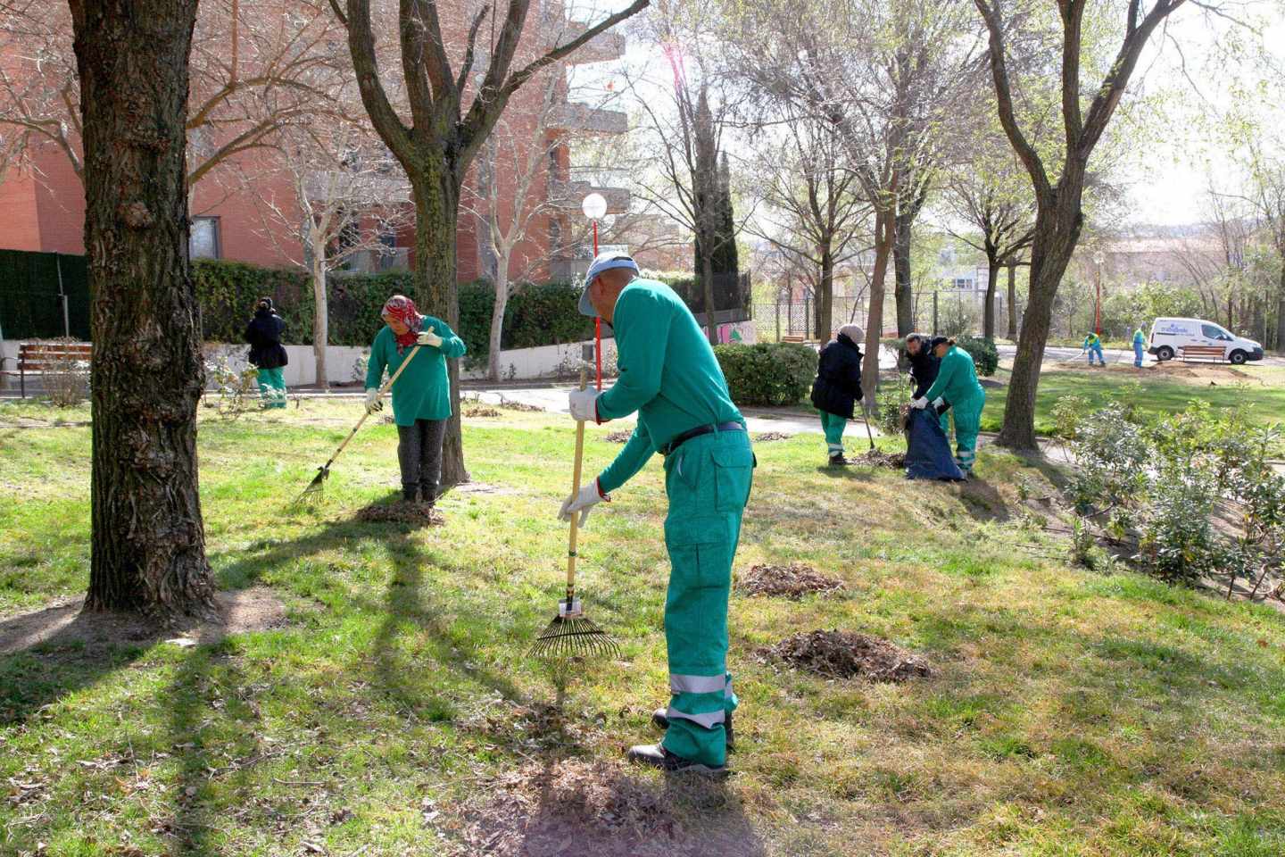 Empleados trabajando en la limpieza de un jardín público.