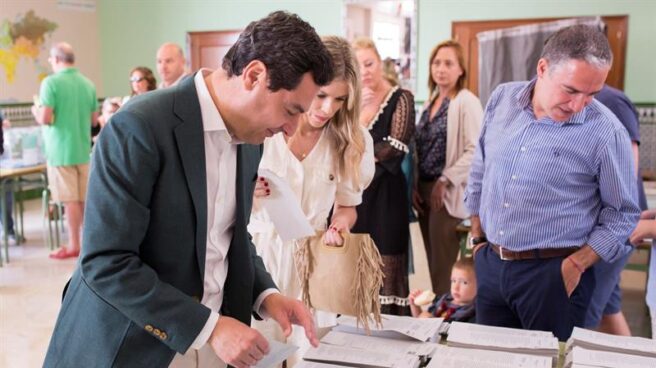 Juan Manuel Moreno busca la papeleta para votar este domingo en el colegio Sagrado Corazón de Málaga.