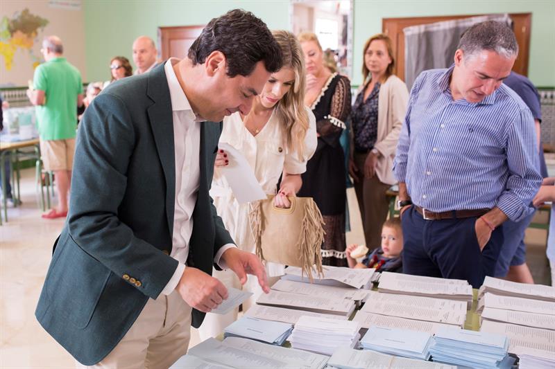 Juan Manuel Moreno busca la papeleta para votar este domingo en el colegio Sagrado Corazón de Málaga.