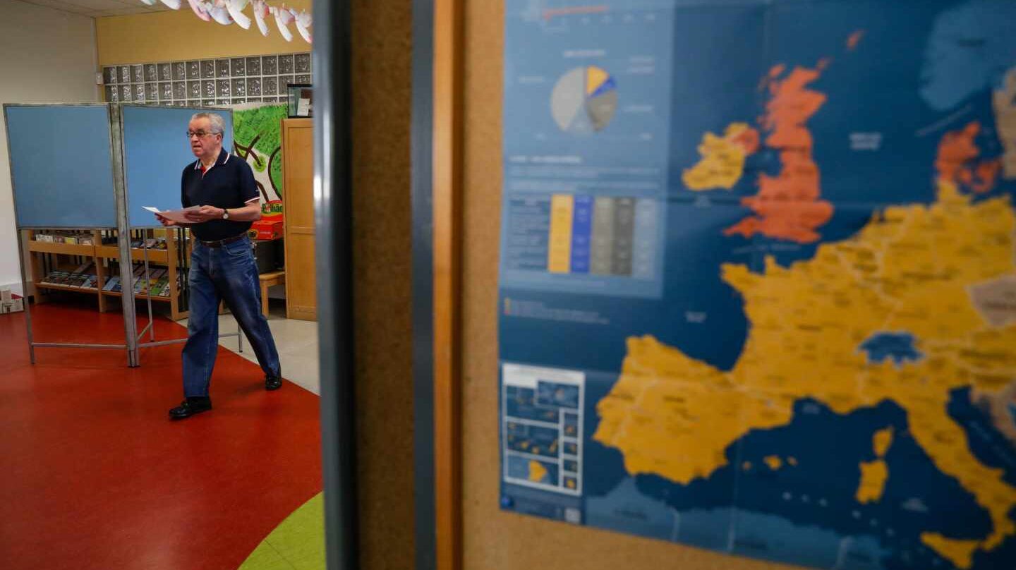 Un votante se dirige a las urnas en un colegio donde se muestra un mapa de Europa.