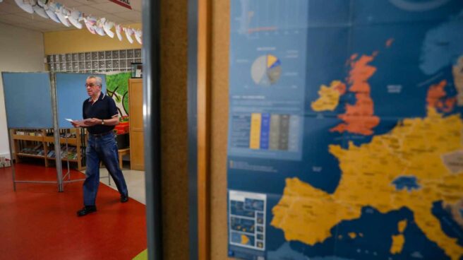 Un votante se dirige a las urnas en un colegio donde se muestra un mapa de Europa.