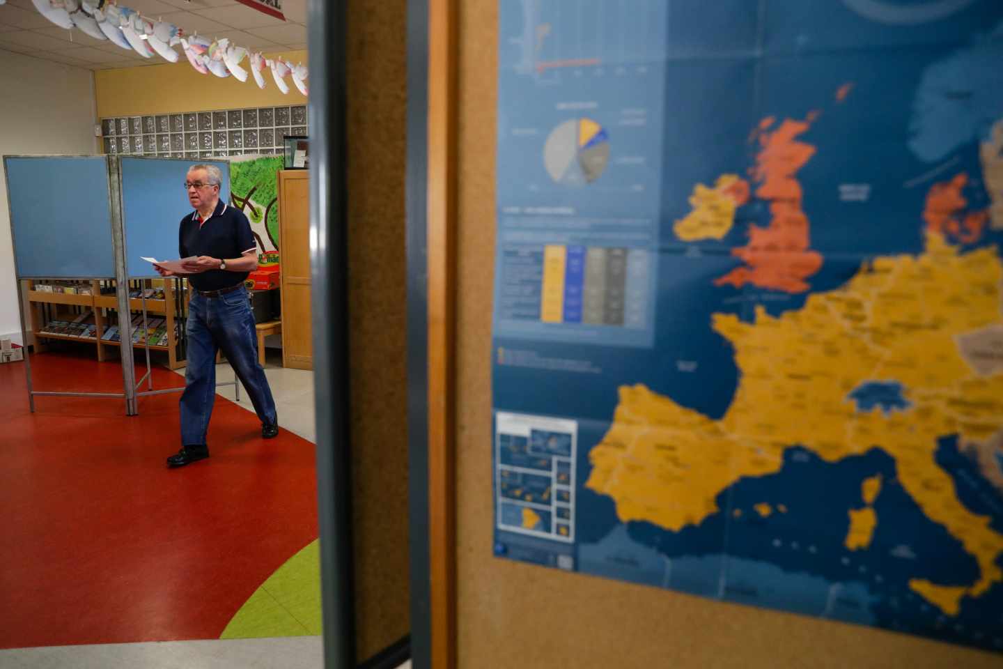 Un votante se dirige a las urnas en un colegio donde se muestra un mapa de Europa.