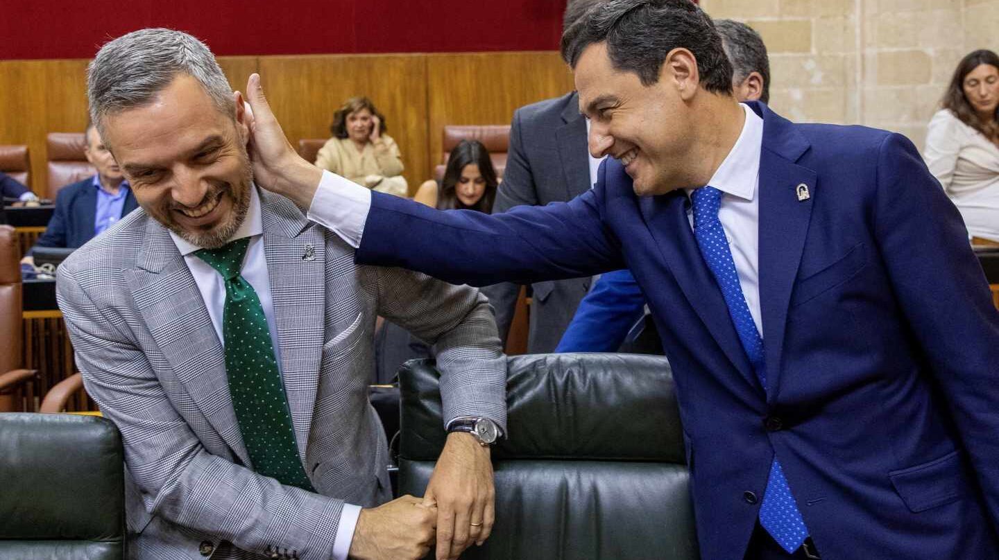 Juanma Moreno bromea con el consejero de Hacienda de la Junta de Andalucía al inicio del pleno.