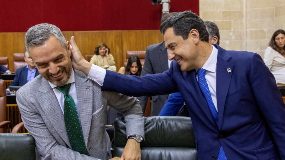 Juanma Moreno bromea con el consejero de Hacienda de la Junta de Andalucía al inicio del pleno.