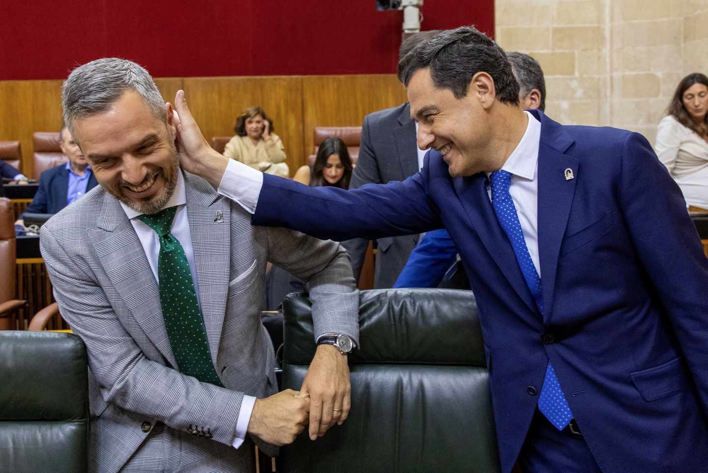 Juanma Moreno bromea con el consejero de Hacienda de la Junta de Andalucía al inicio del pleno.