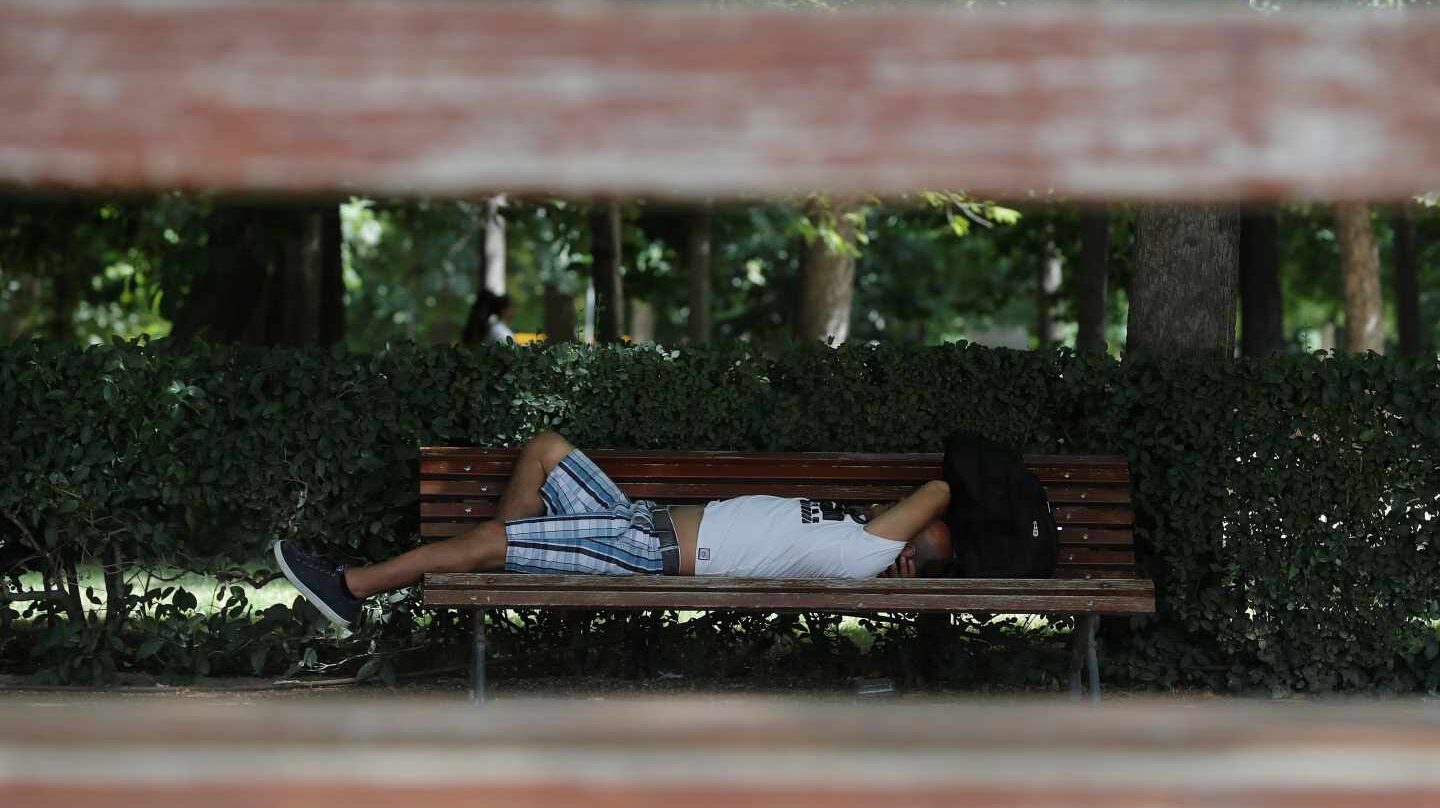 Un hombre, tumbado en un banco durante la ola de calor.