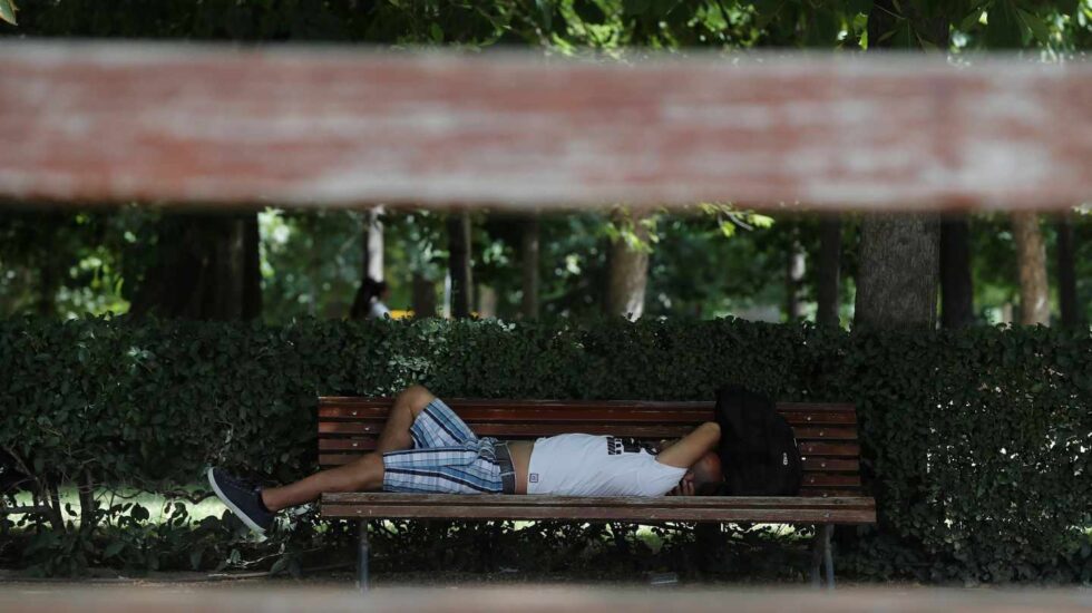 Un hombre, tumbado en un banco durante la ola de calor.