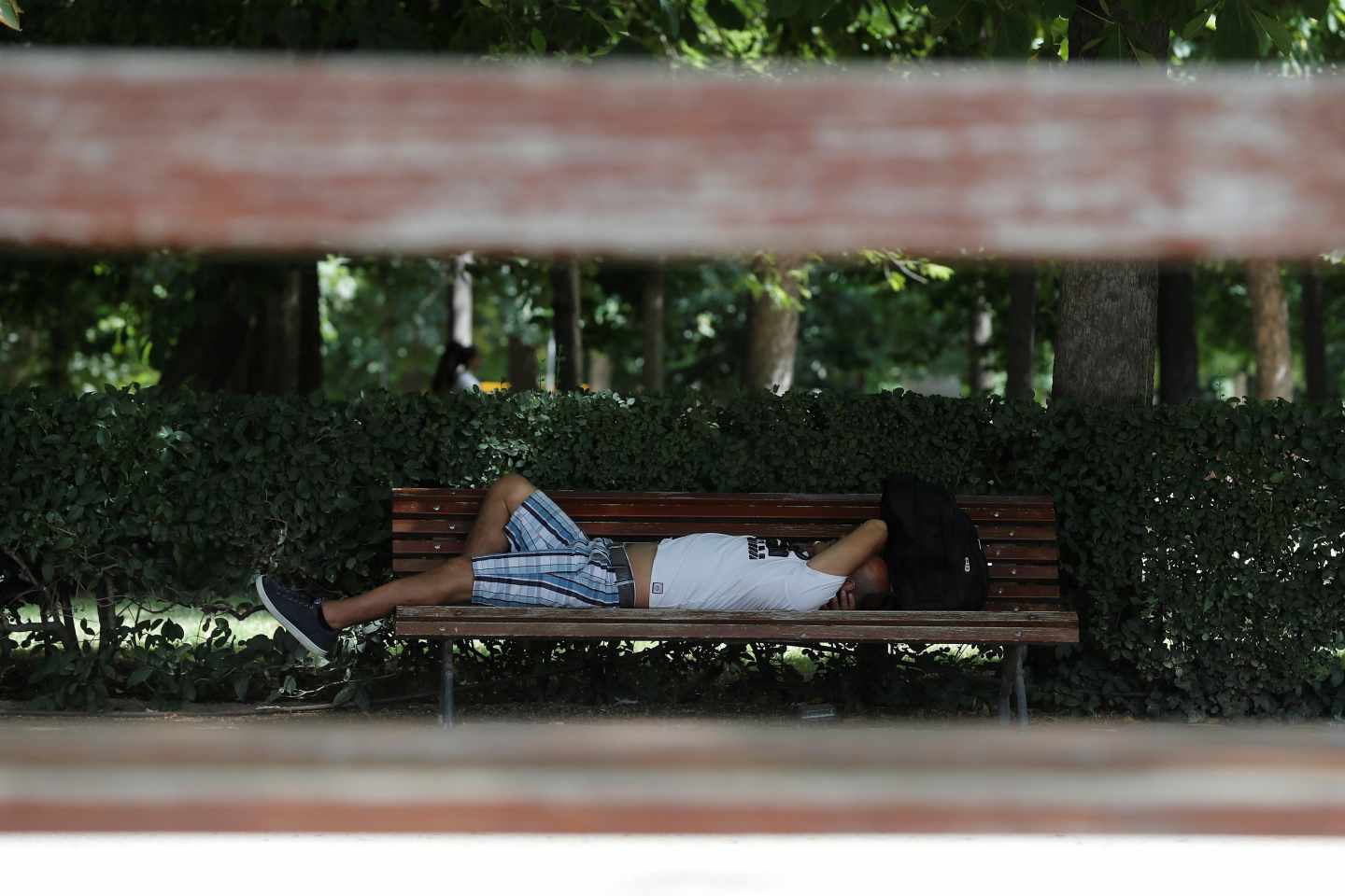 Un hombre, tumbado en un banco durante la ola de calor.