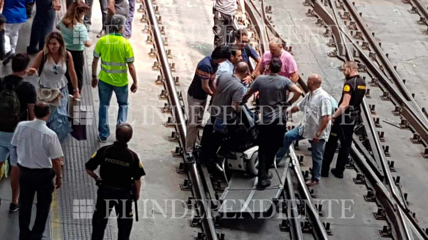 Varias personas en las vías de Atocha rodean la rampa habilitada para las personas con movilidad reducida.