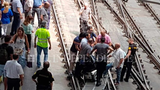 Varias personas en las vías de Atocha rodean la rampa habilitada para las personas con movilidad reducida.