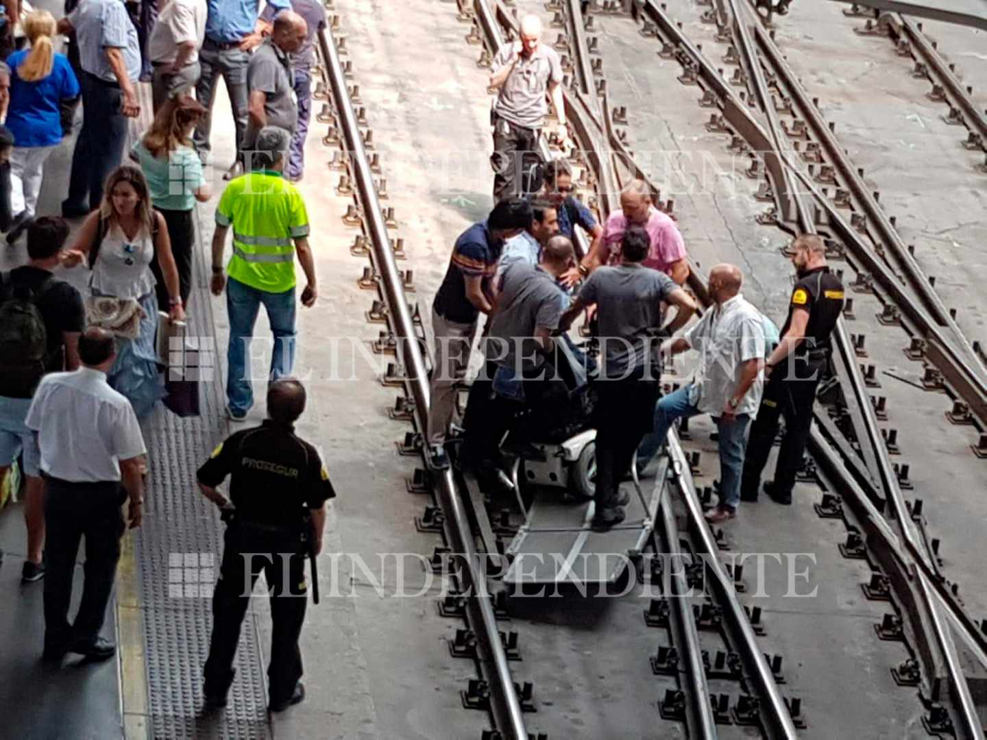 Varias personas en las vías de Atocha rodean la rampa habilitada para las personas con movilidad reducida.