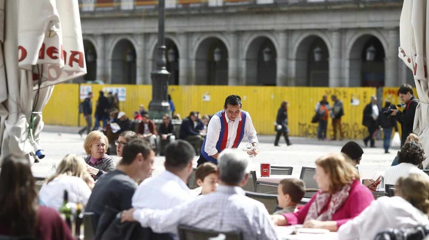 Un camarero sirve mesas en una terraza de Madrid.