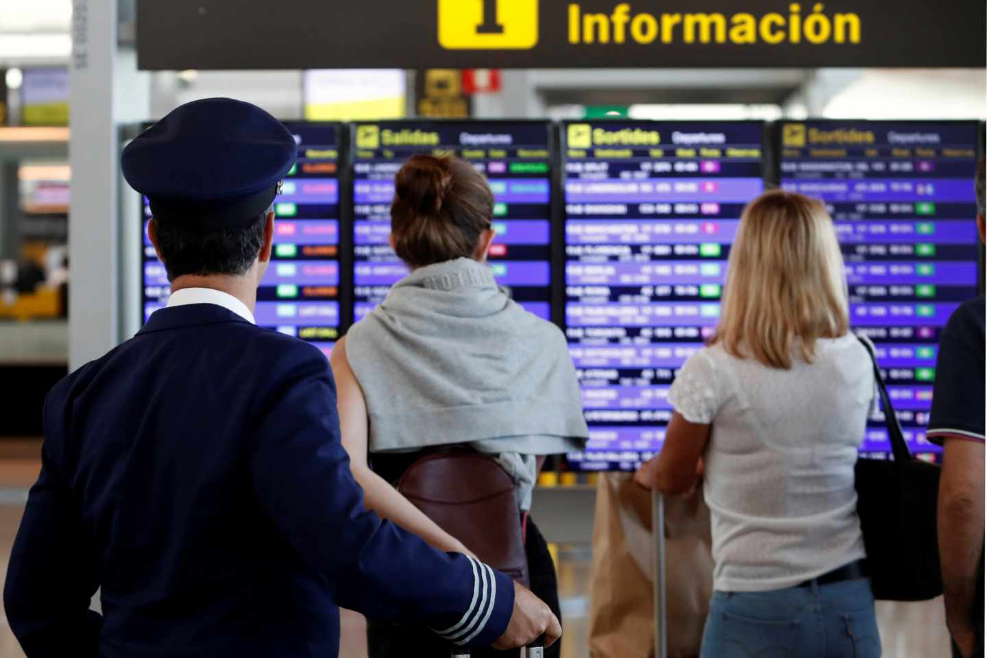 Pasajeros mirando el panel de vuelos en el aeropuerto El Prat.