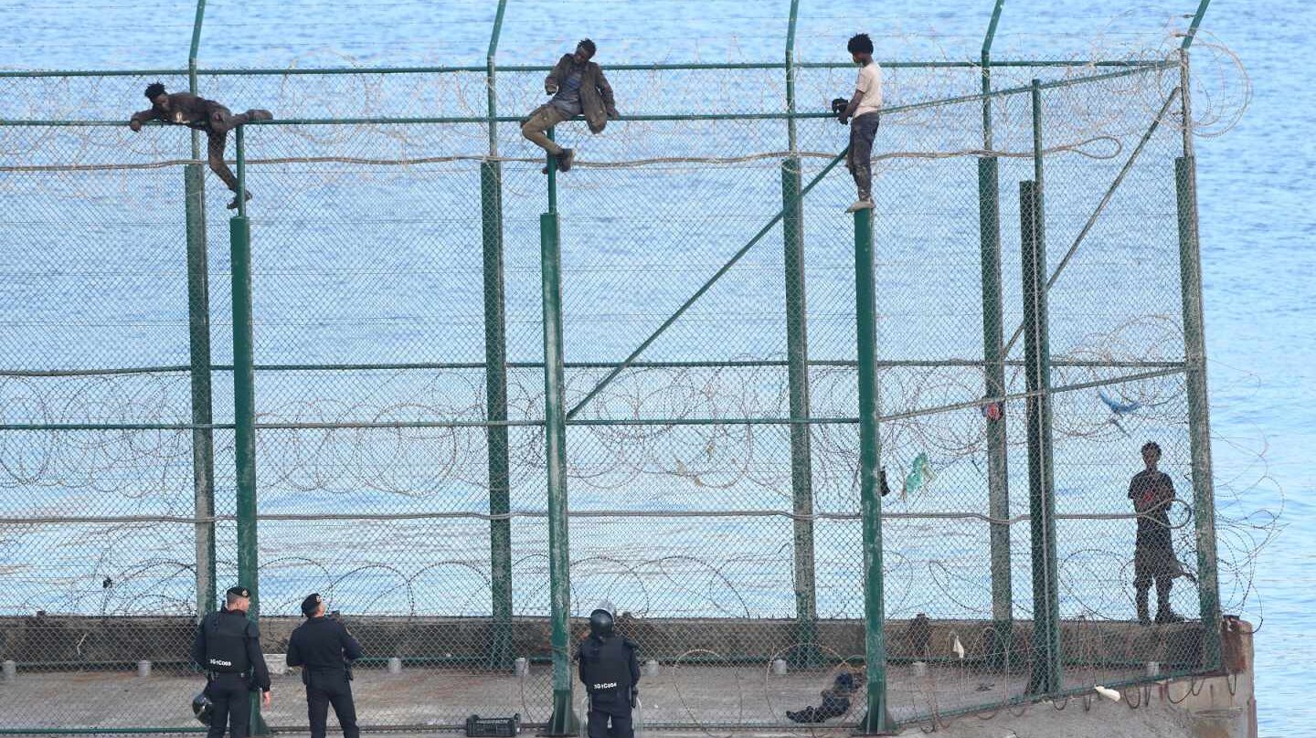 Migrantes, encaramados en la valla fronteriza de Ceuta.