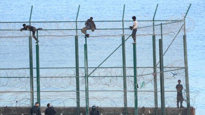 Migrantes, encaramados en la valla fronteriza de Ceuta.