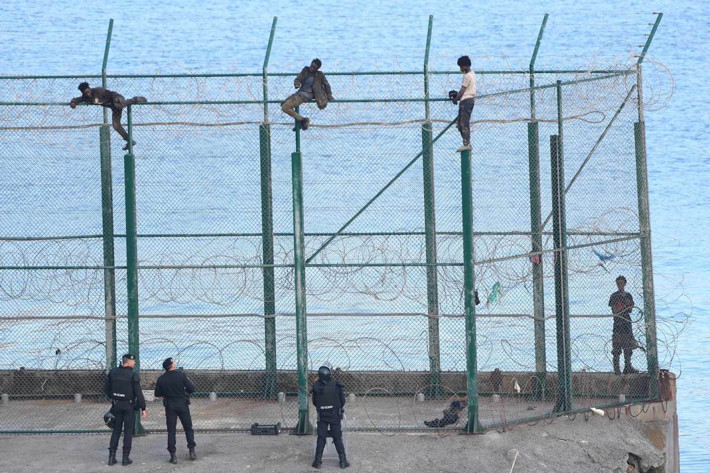Migrantes, encaramados en la valla fronteriza de Ceuta.