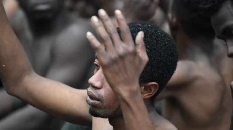 Uno de los de 153 migrantes, levanta los brazo a su entrada en Ceuta saltando su doble valla en lo que ha sido la primera incursión en grupo en un año.