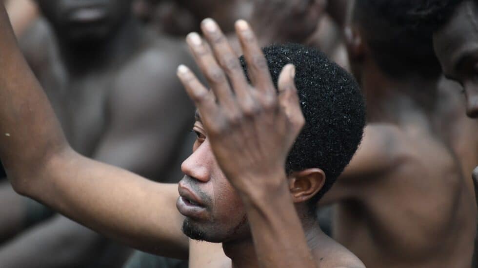 Uno de los de 153 migrantes, levanta los brazo a su entrada en Ceuta saltando su doble valla en lo que ha sido la primera incursión en grupo en un año.