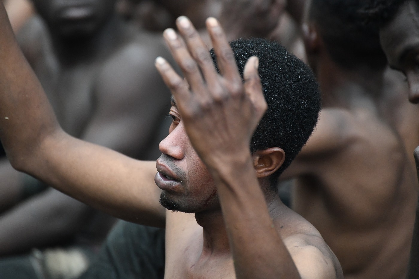 Uno de los de 153 migrantes, levanta los brazo a su entrada en Ceuta saltando su doble valla en lo que ha sido la primera incursión en grupo en un año.