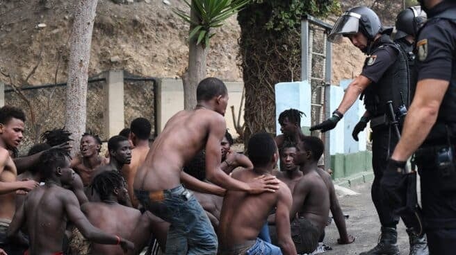 Uno de los de 153 migrantes, levanta los brazo a su entrada en Ceuta saltando su doble valla en lo que ha sido la primera incursión en grupo en un año.