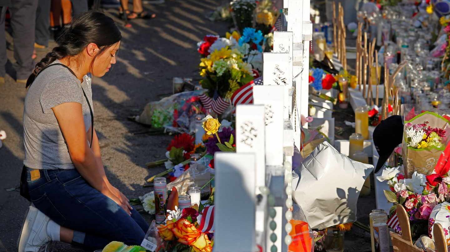 Una mujer se arrodilla ante las cruces en recuerdo de las víctimas mortales en El Paso.