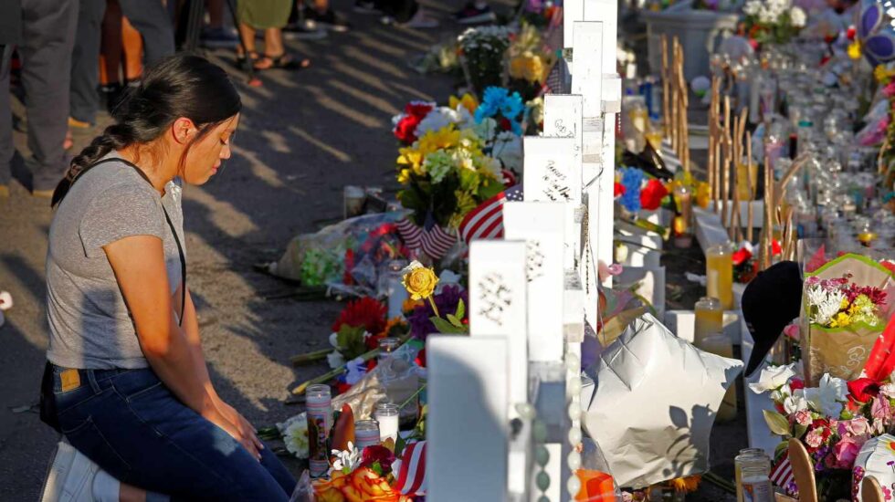 Una mujer se arrodilla ante las cruces en recuerdo de las víctimas mortales en El Paso.