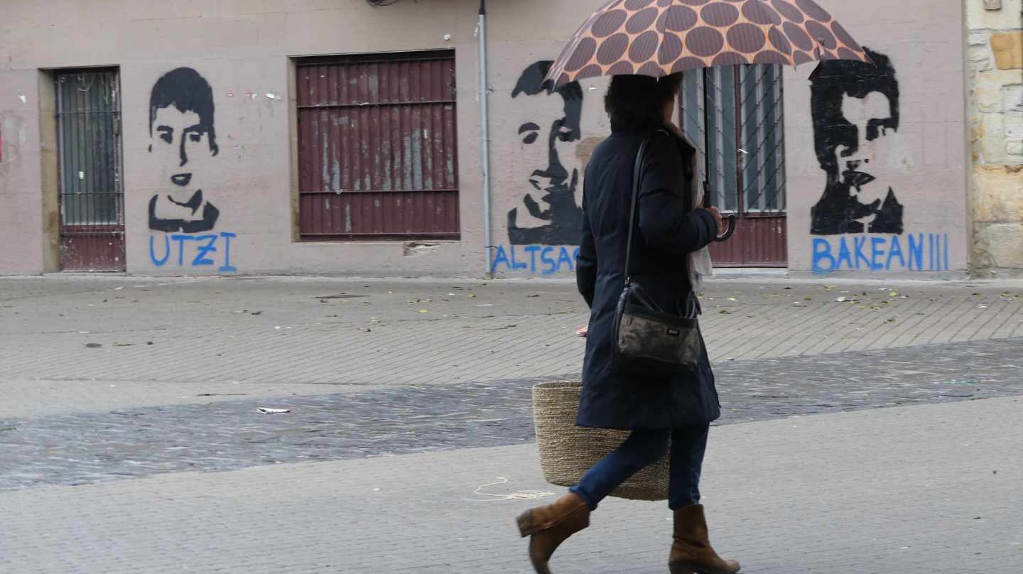 Una mujer pasa frente a los retratos de tres de los condenados.