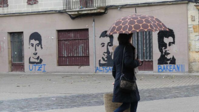 Una mujer pasa frente a los retratos de tres de los condenados. Una mujer pasa frente a los retratos de tres de los condenados.