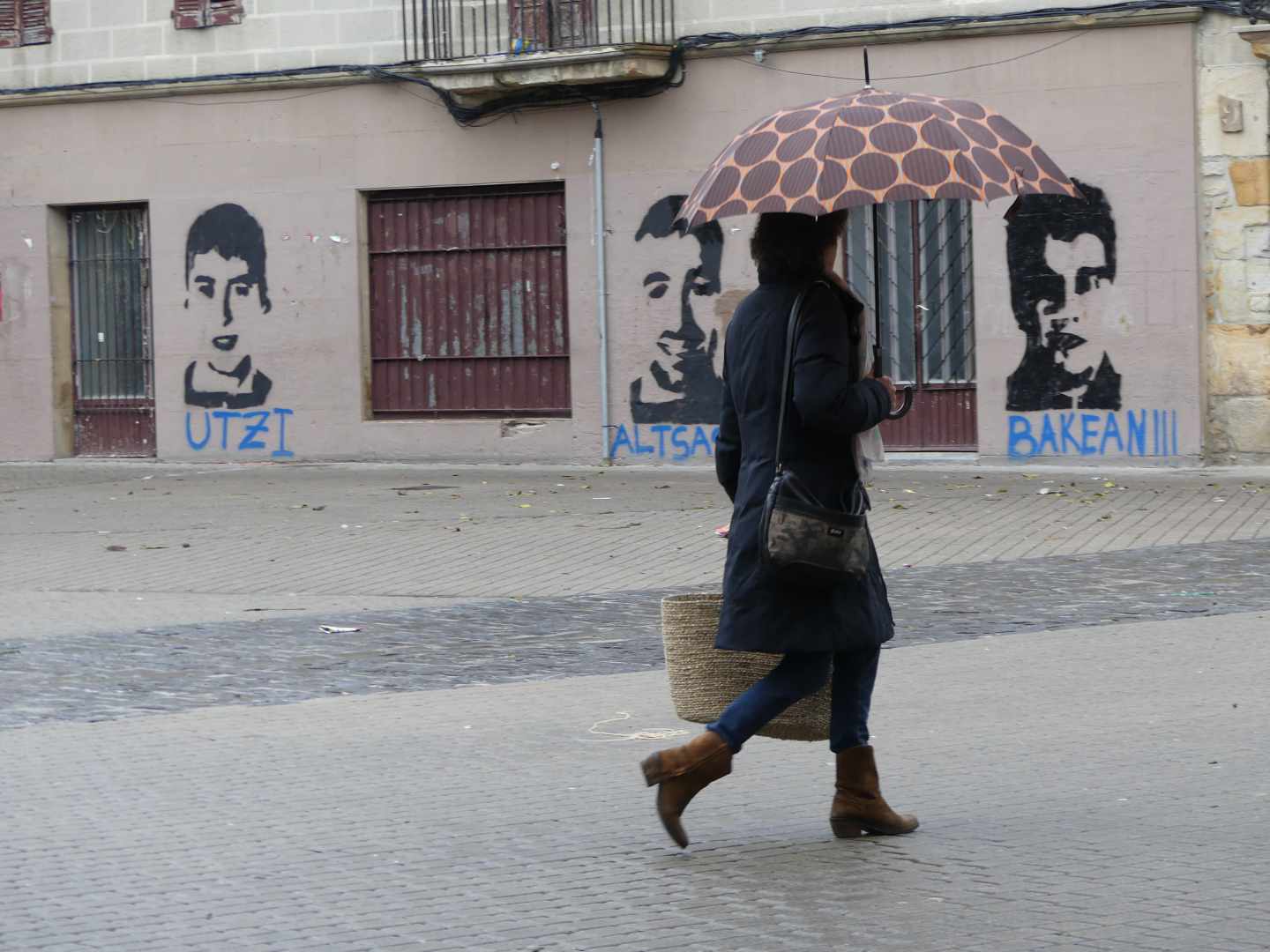 Una mujer pasa frente a los retratos de tres de los condenados.