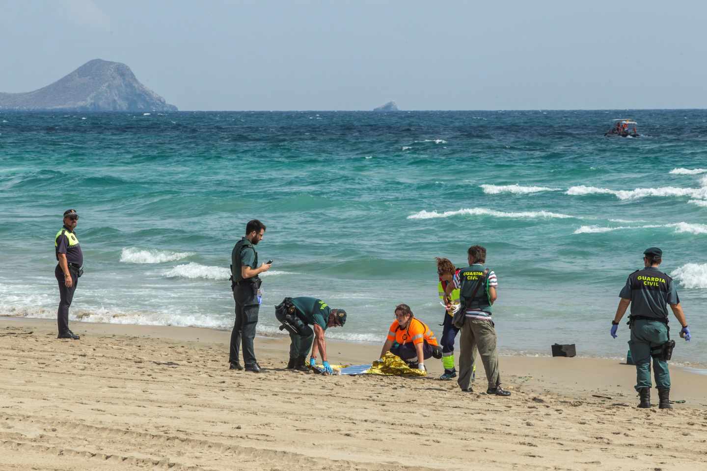 Agentes de la Guardia Civil y miembros de los servicios de Emergencias buscan restos del aparato siniestrado en una playa de la zona.