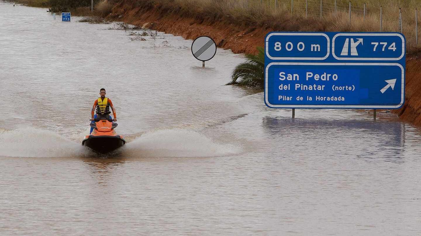 Un miembro de los servicios de rescate cruza la autopista AP-7 en moto acuática
