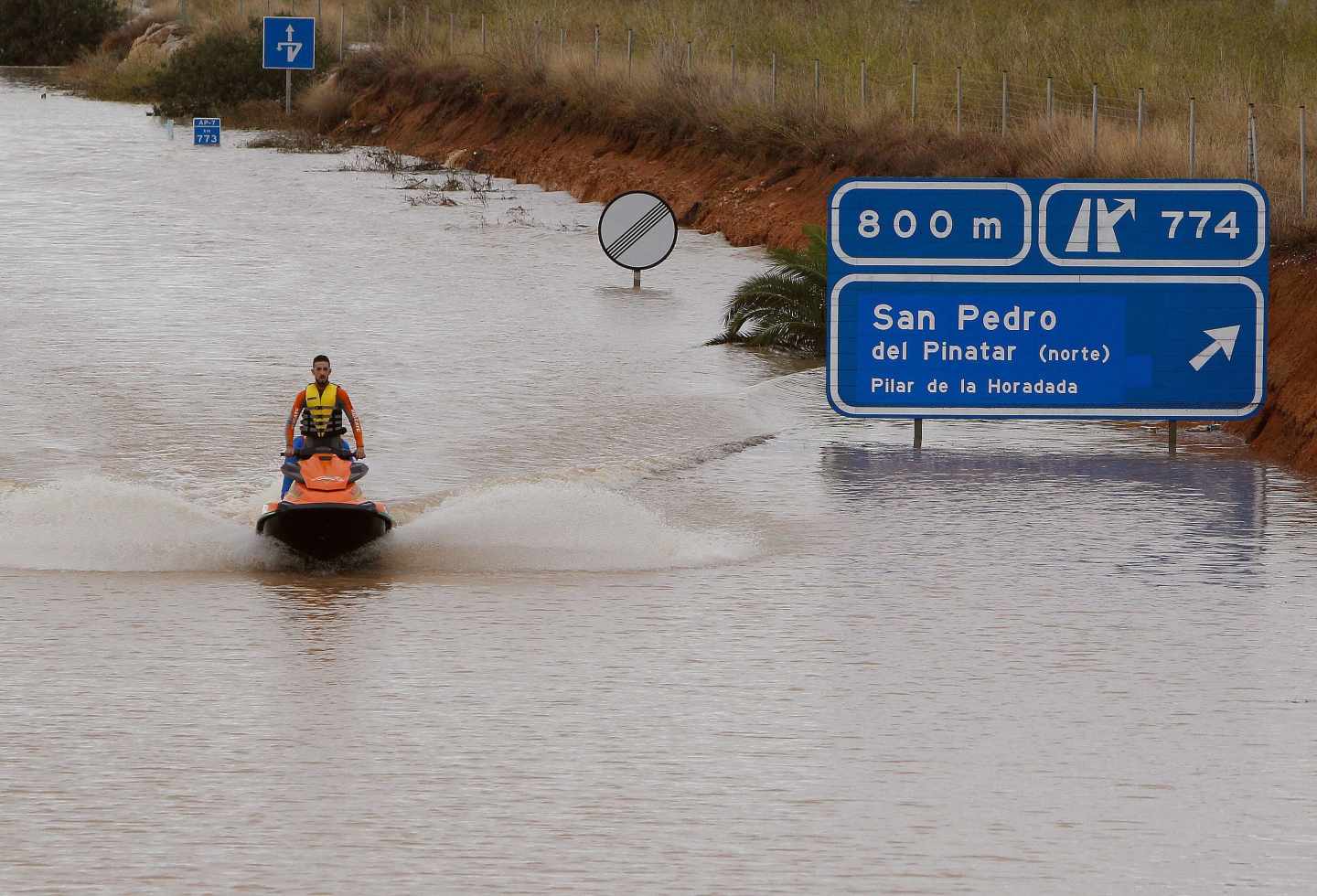 Un miembro de los servicios de rescate cruza la autopista AP-7 en moto acuática